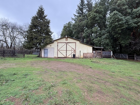 Open pasture with a white barn at the treeline